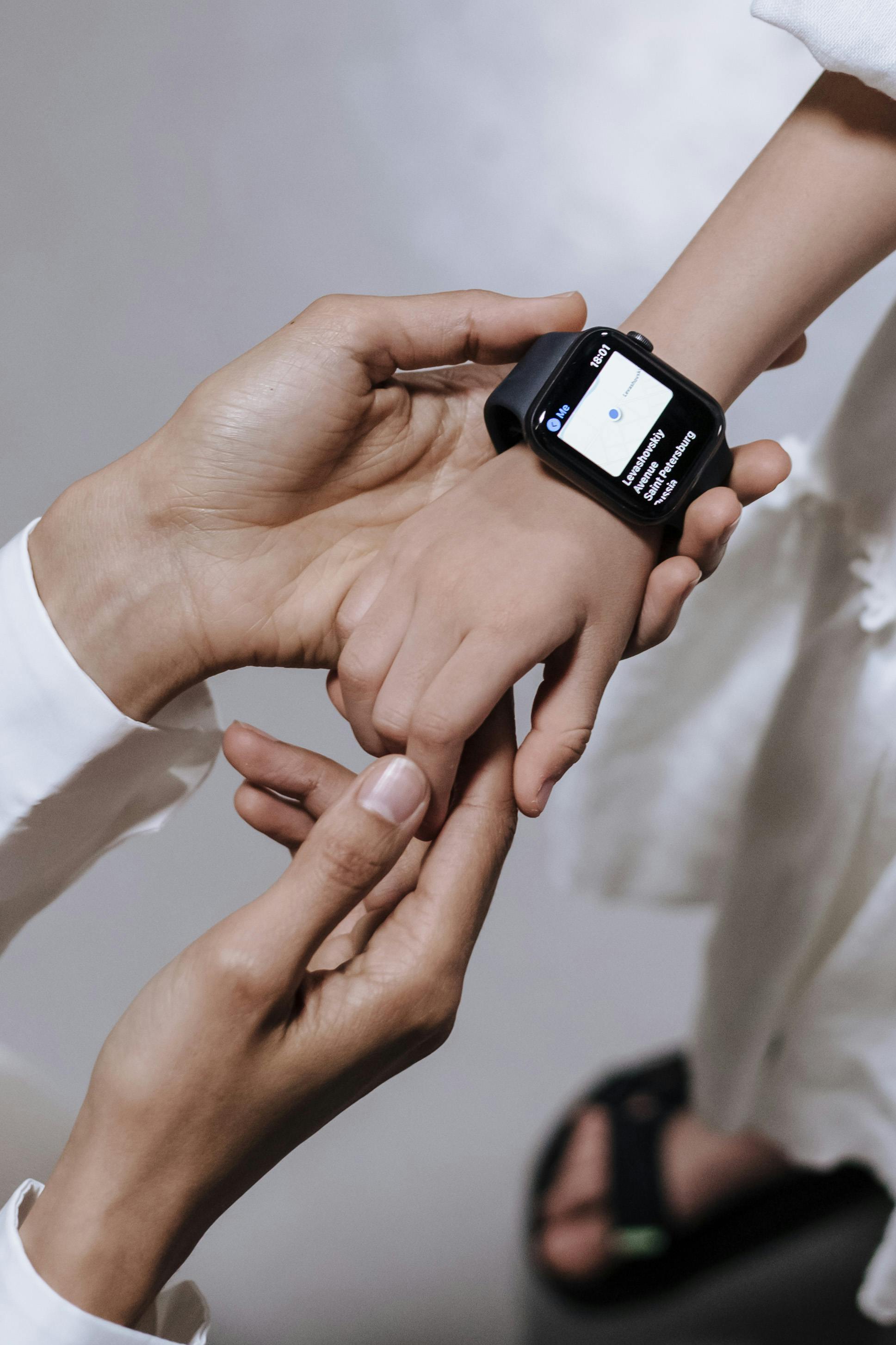 A mother assists her child with wearing a smartwatch, focusing on family and technology.