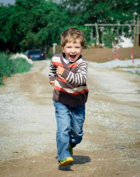 A young boy joyfully runs down a path, showcasing playful energy in a Czech outdoor setting.